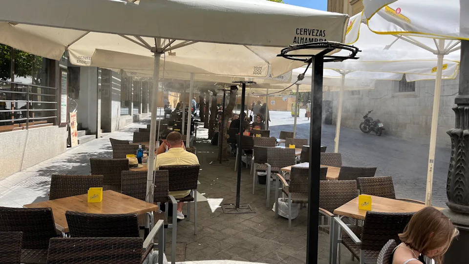 Customers sit beneath water misters in a cafe