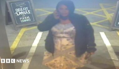 A woman wearing a black jacket and hood on the phone