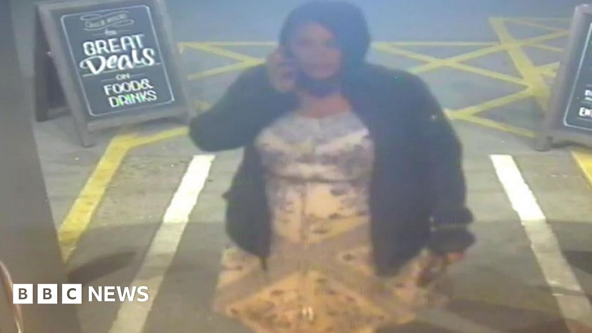 A woman wearing a black jacket and hood on the phone