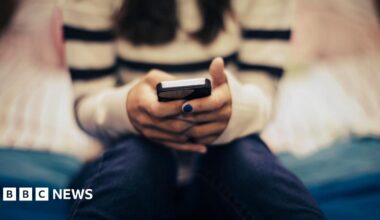 A generic, blurred image showing a young person with painted nails texting on a smartphone.