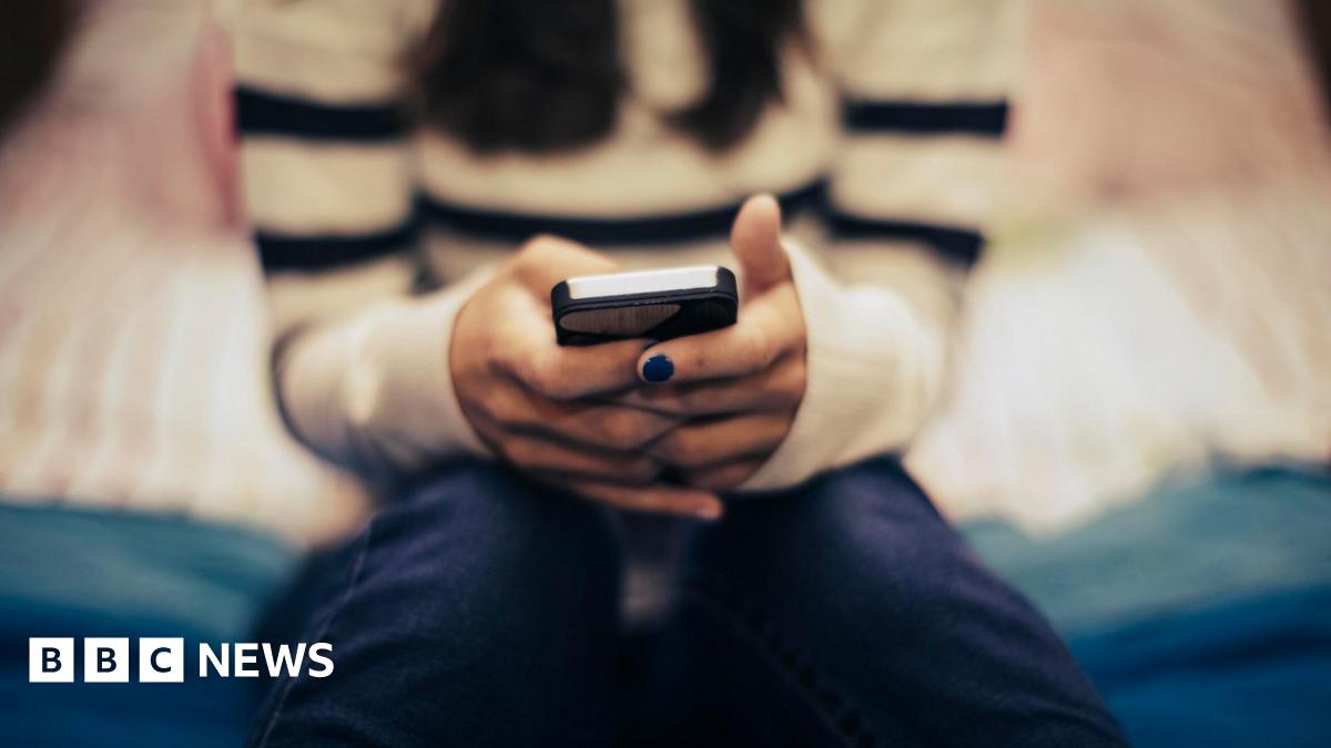 A generic, blurred image showing a young person with painted nails texting on a smartphone.