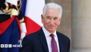 United States Ambassador to France Charles Kushner is pictured smiling outside the Elysee palace in Paris. He has white hair and is wearing a dark coloured suit, white shirt with a plum coloured tie.