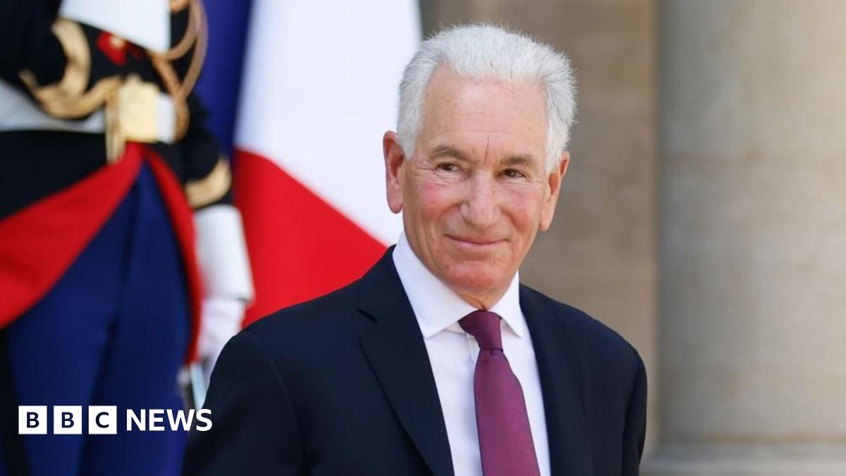 United States Ambassador to France Charles Kushner is pictured smiling outside the Elysee palace in Paris. He has white hair and is wearing a dark coloured suit, white shirt with a plum coloured tie.