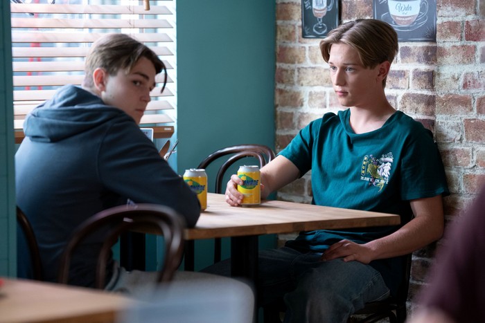 Tommy looking off to the side as Joel looks his way in EastEnders