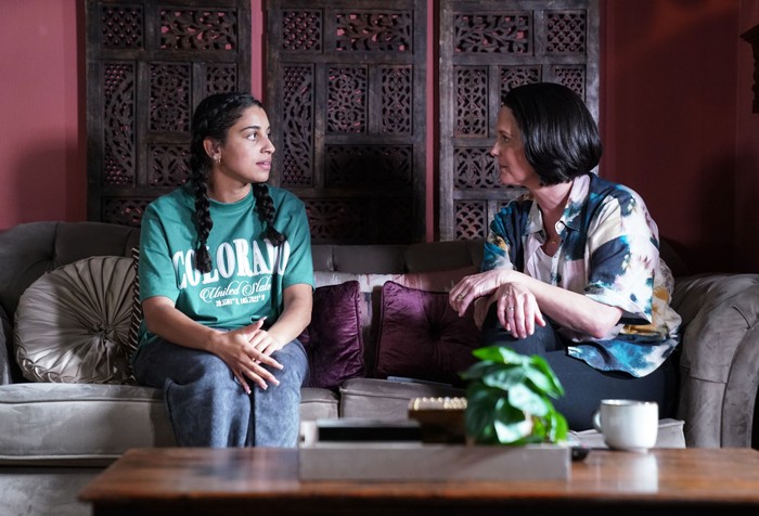 Avani and Eve sitting side by side looking worried in EastEnders