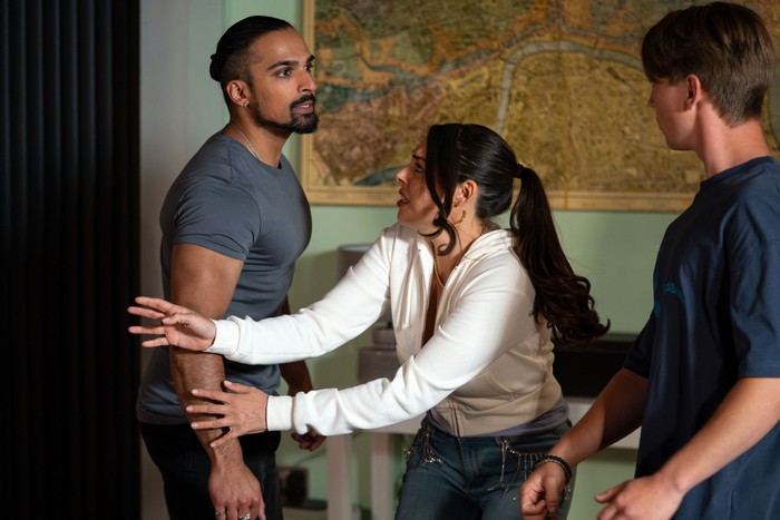 Aaron Thiara as Ravi Gulati is held back by Sophie Khan Levy as Priya Nandra-Hart from Max Murray as Joel Marshall in the Panesar house in EastEnders.