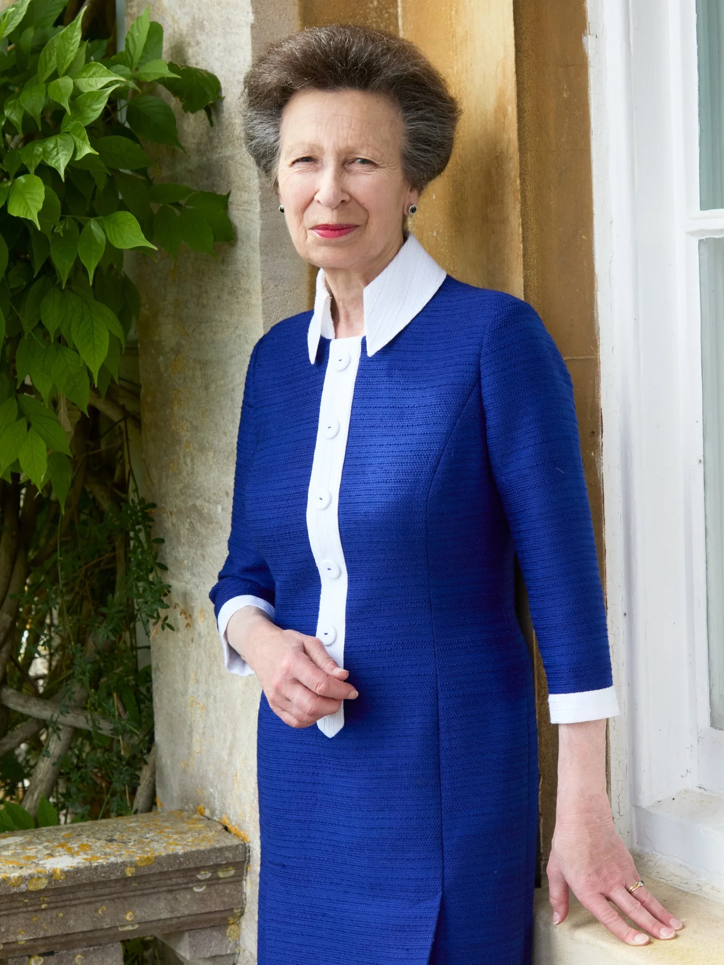 Princess Anne stans in a blue and white dress