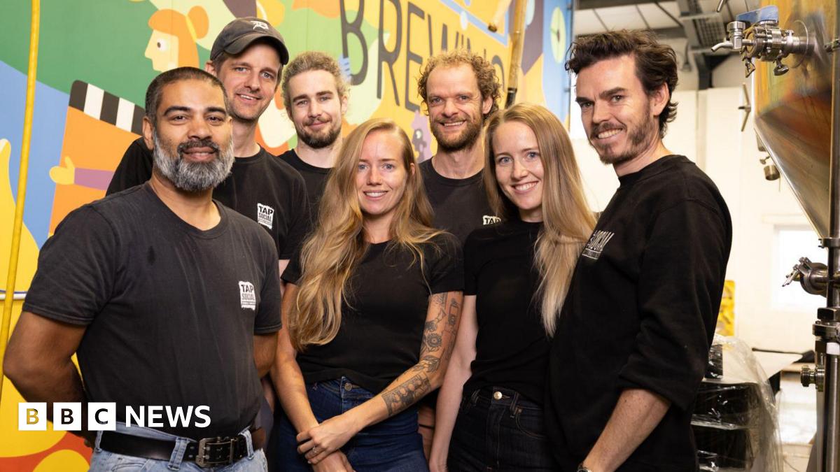 The Tap Social Movement team smiling for a picture at the brewery, including founders Tess and Amy Taylor, and Paul Humpherson, who are in the first row.