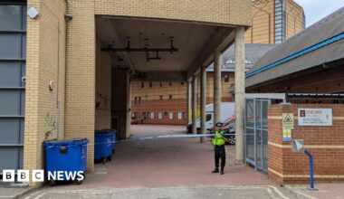 A police officer stands guard next to some police tape.