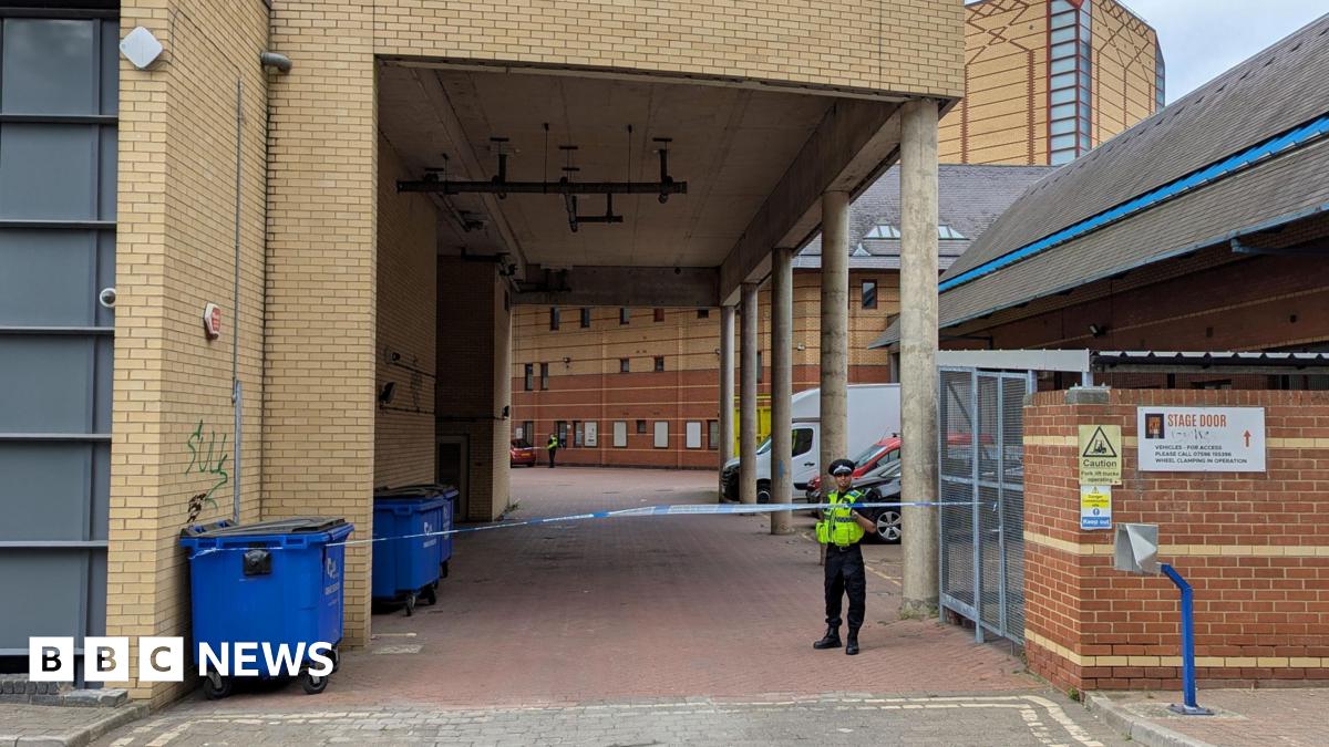 A police officer stands guard next to some police tape.