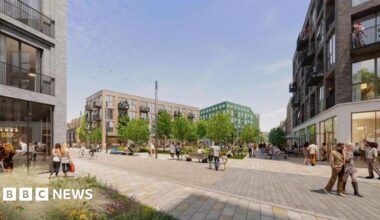 A 3d generated image of what hind street development could look like. There are several three story buildings around a small green space with trees. There a pedestrian walkways, full of people walking.