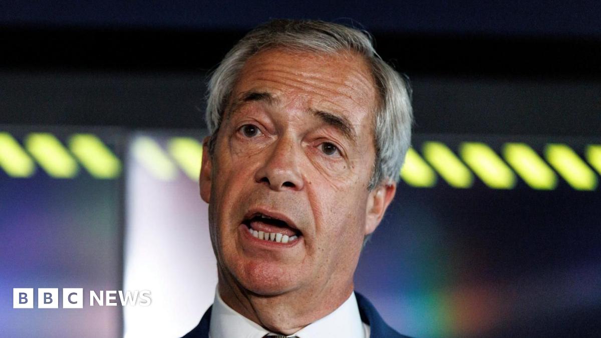 Nigel Farage, wearing a white shirt and navy blazer, tilts his head to one side as he speaks