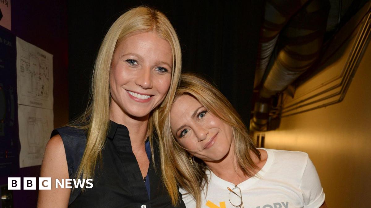Gwyneth Paltrow and Jennifer Aniston standing close together, Aniston's head is on Paltrow's shoulder