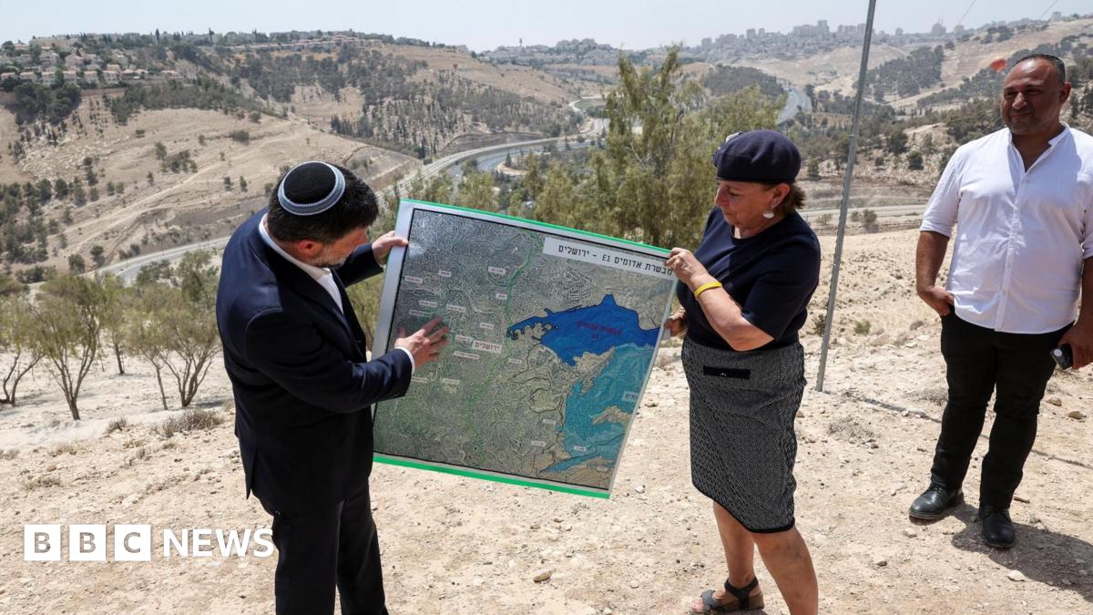 Israeli Finance Minister Bezalel Smotrich (L) helps to hold up a map showing the plans for the E1 settlement project during a visit to the area, in the occupied West Bank, on 14 August 2025