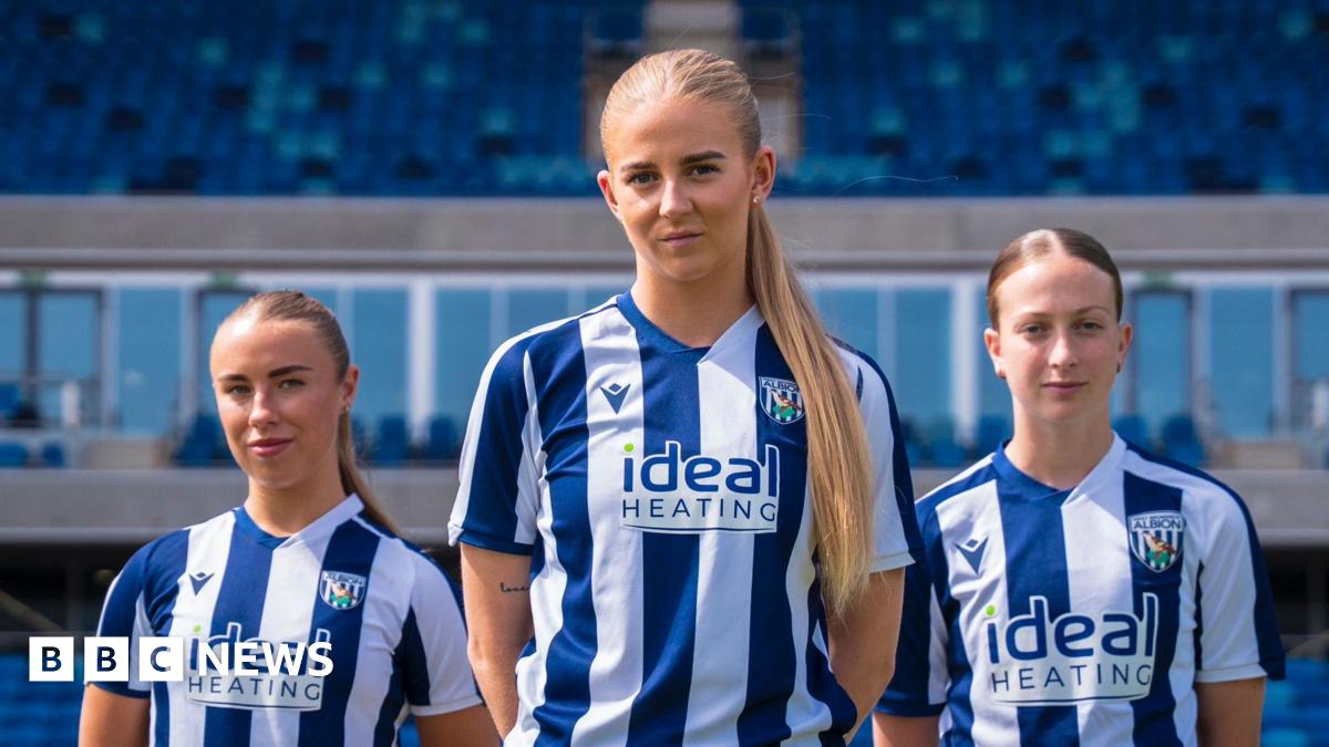 Three female football players stand in blue and white West Bromwich Albion kits in a football stadium.