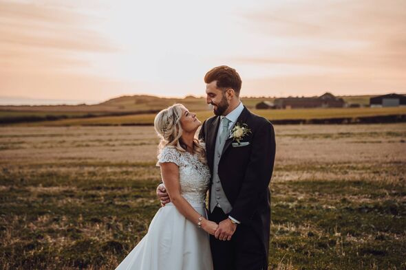 A couple looking at each other at sunset in their wedding outfits