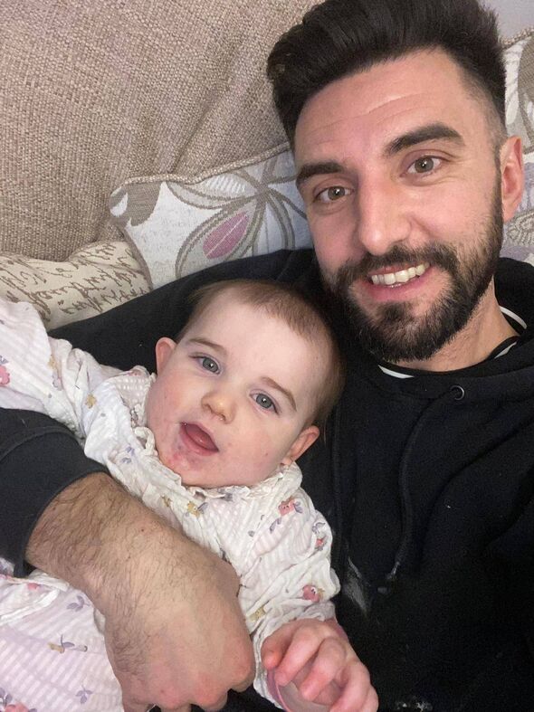 A man holding a baby girl and smiling at the camera