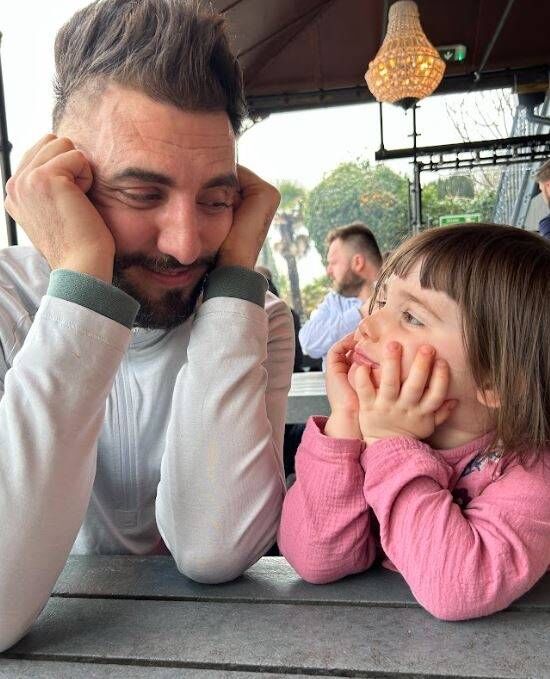 A dad with his daughter smiling at each other