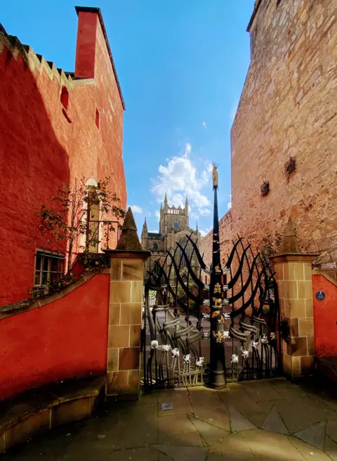 Pete Carnochan A beautiful ornate black iron gate leads to the cemetery surrounding Dunfermline Abbey - the red walls on either side adding to the drama.