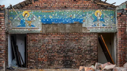 Great Places Housing Group The exposed gable end of one of the convent buildings, which has been partially demolished, and has exposed a mosaic of two angels facing each other from opposite sides of the building.