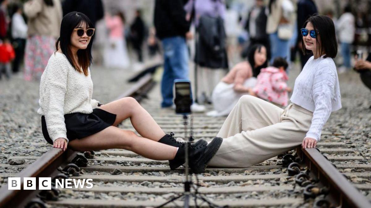 Two women pose for selfies as they visit the disused Gyeonghwa Station railway track during the Jinhae Cherry Blossom Festival in Changwon