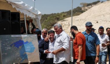 Finance Minister Bezalel Smotrich interacts with a man, on the day of a press conference regarding settlements expansion for the long-frozen E1 settlement, that would split east Jerusalem from the West Bank, near the Israeli settlement of Ma'aleh Adumim, August 14, 2025.