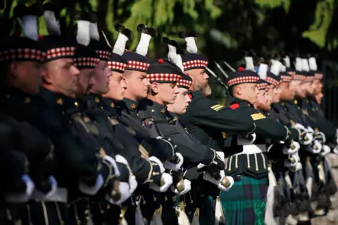 PA Media Members of Balaklava Company, 5th Battalion, The Royal Regiment of Scotland, stand in line at the gates of Balmoral