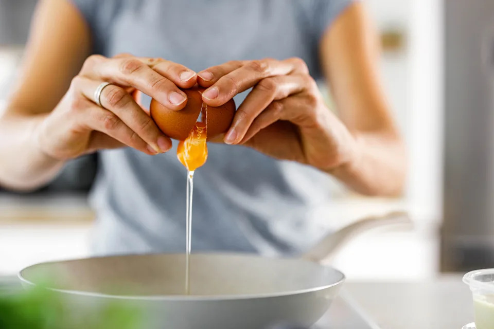 Close up of unrecognizable woman cracking an egg into a bowl.