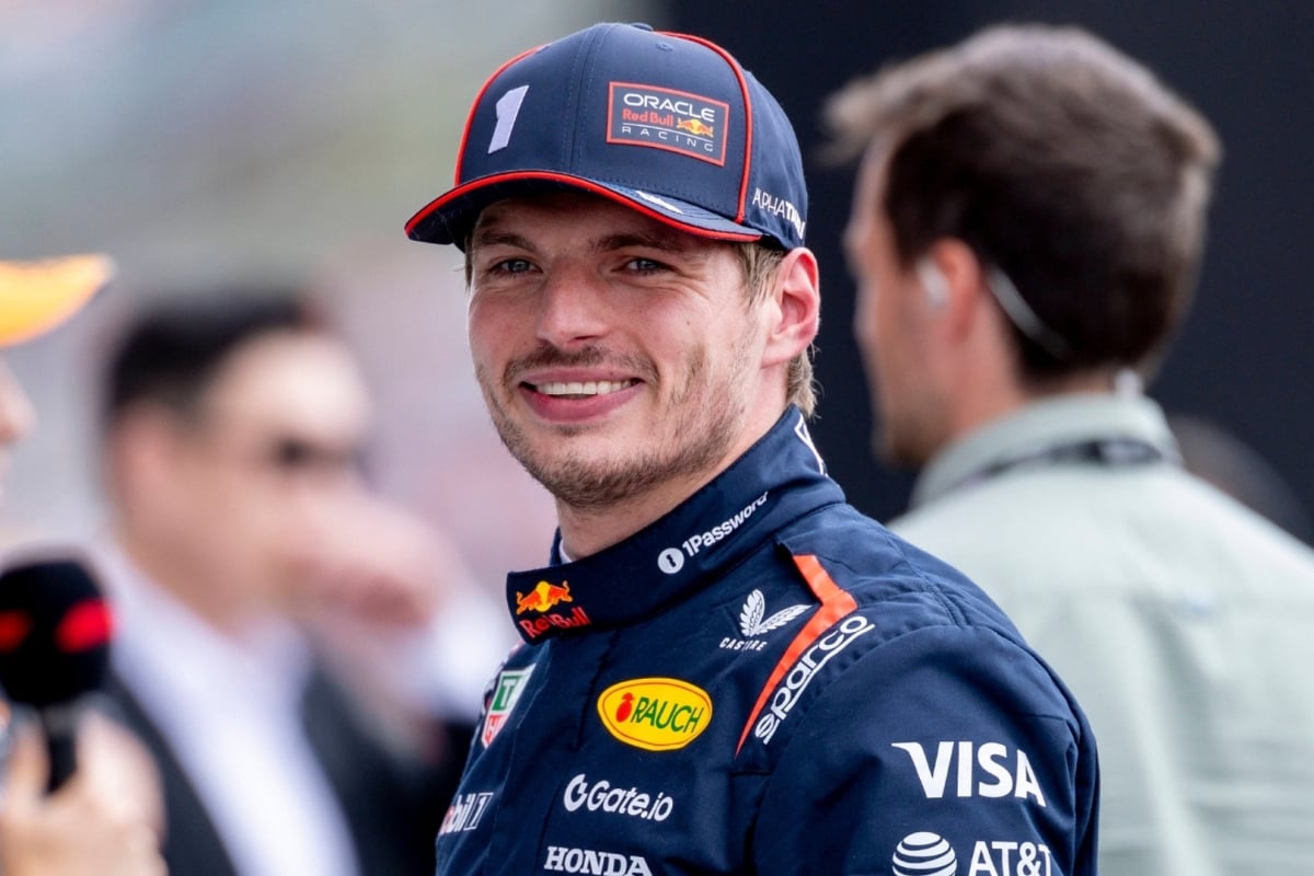 Max Verstappen smiling at the camera in Red Bull F1 team kit