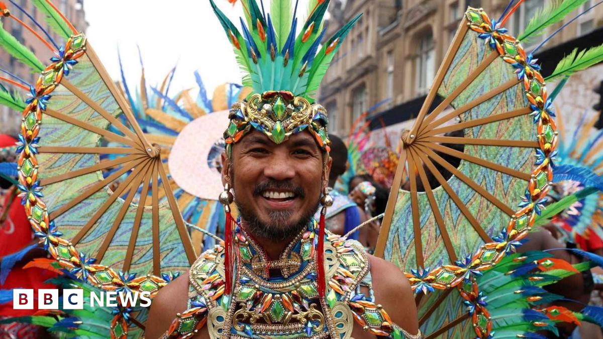 man at the carnival dressed up in green and blue feathers
