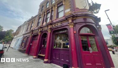 Exterior shows purple Queen of the South pub with double doors and glass windows
