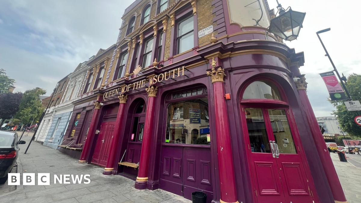 Exterior shows purple Queen of the South pub with double doors and glass windows