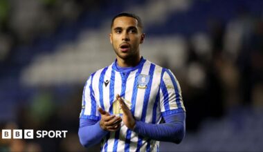Defender Max Lowe wearing a blue and white striped Sheffield Wednesday shirt claps with a disappointed look on his face