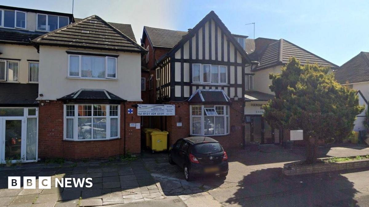 The outside of a red brick house with victorian style crosshatching on the to half. It is a nursing home with a black car parked outside.