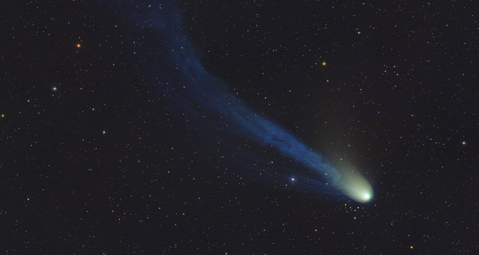 a bright dot leaves a hazy trail behind it as it flies in front of background stars