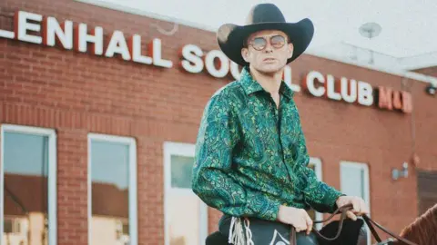Ryan Dunn Kevin Donnelly sat on horseback wearing a green patterned shirt and a black Stetson outside WillenHall Social Club. 