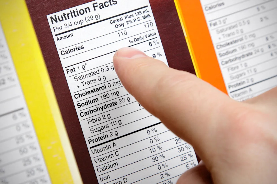 A close-up of a concerned shopper checking the nutrition labels of various boxes of cereal.