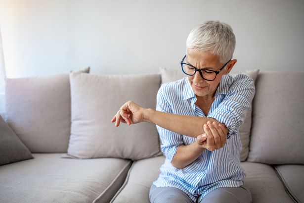 Senior woman suffering from pain in hand at home. 
