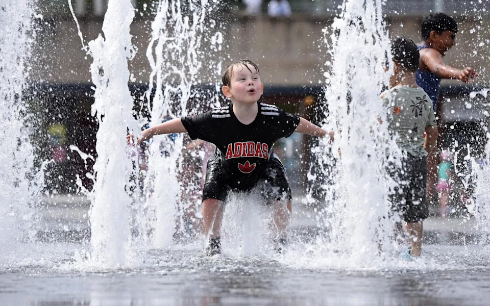 Carson Clifford, aged 4, cools off in the hot weather among fountains in City Park, Bradford City Centre