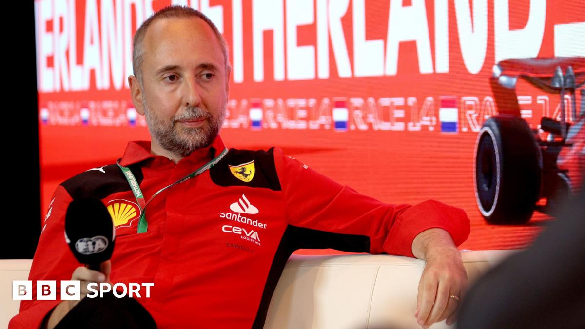 Enrico Cardile wearing a Ferrari top and holding an FIA-branded microphone