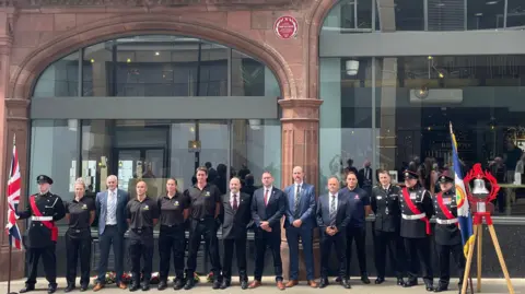 Tom MacDougall/BBC Members of South Yorkshire Fire and Rescue and the Fire Brigades Union stood underneath the commemorative red plaque, which has been unveiled at Brown's Brasserie and Bar on Norfolk Street.