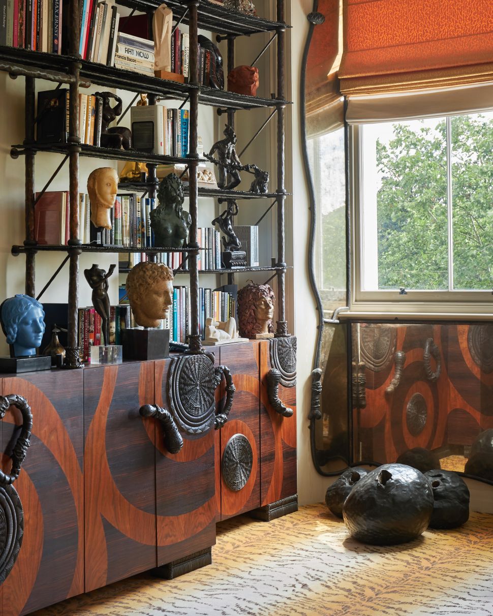 A detail of Pauline Karpidas’s drawing room featuring a custom-designed bookcase by Mattia Bonetti, filled with books, sculptures, and eclectic objects.