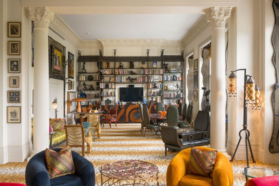 A wide view of Pauline Karpidas’s London salon, featuring eclectic furniture, art-filled walls, and a bookcase designed by Mattia Bonetti.