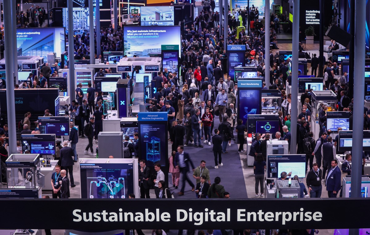 A crowd of tech workers is seen mingling at an industrial trade fair.