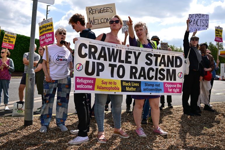 people hold a colourful sign saying Crawley stand up to racism at a small protest