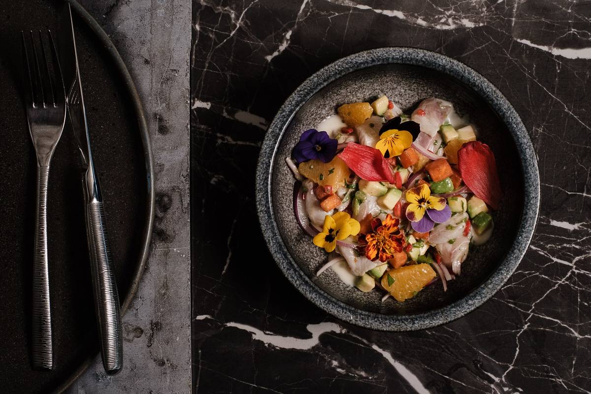 a japanese dish of cured fish and fruit presented on a marble countertop