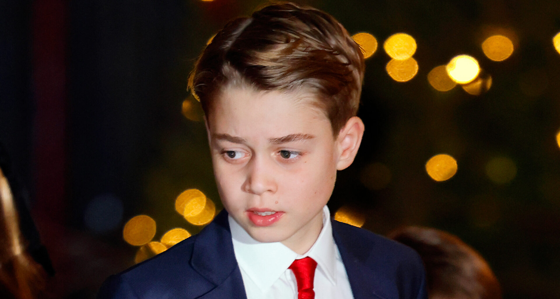 Prince George wearing a navy suit, white shirt, red tie