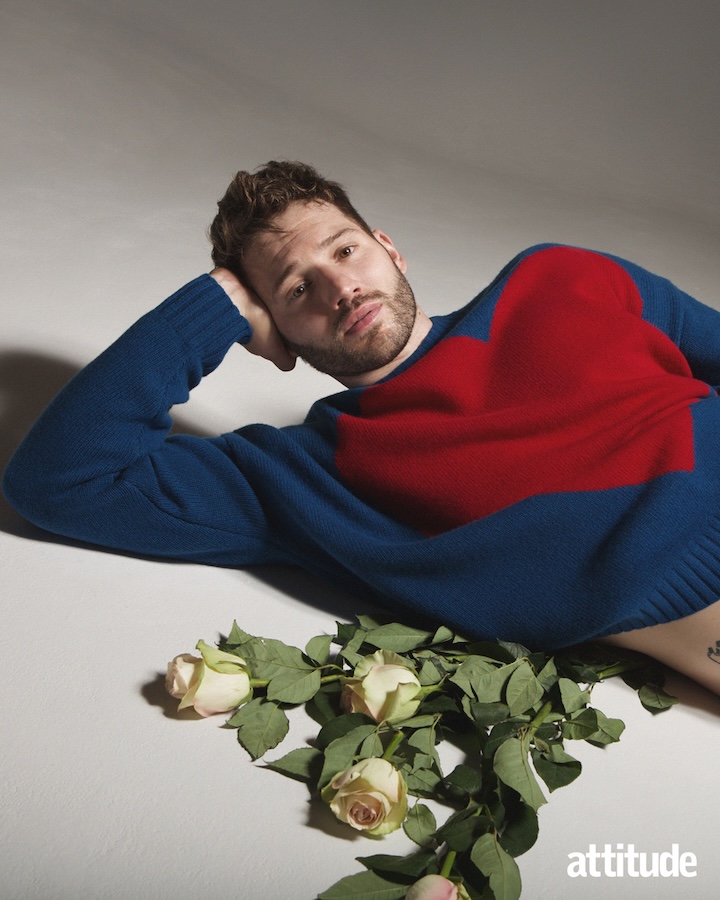 Alexander lying on the ground with flowers wearing a jumper with a red heart on it