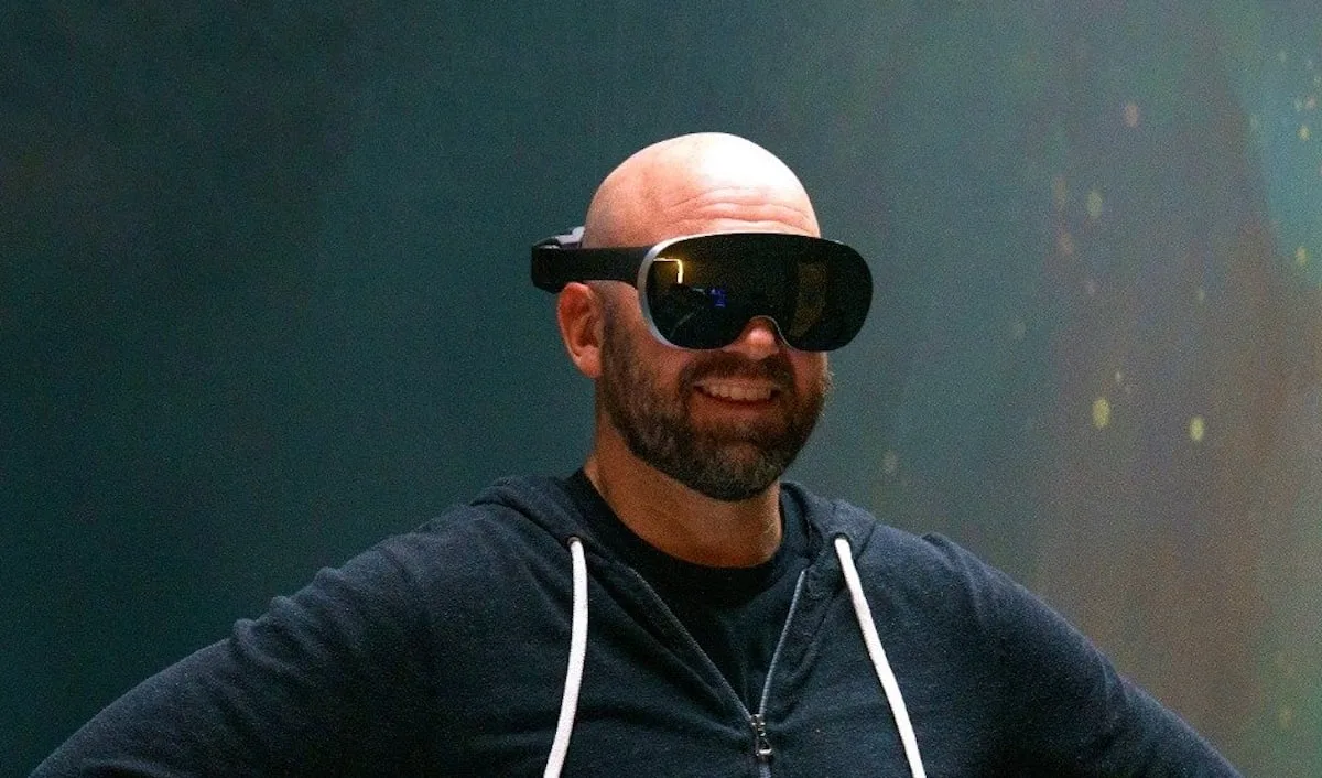 Meta CTO Andrew Bosworth smiling while wearing a Meta Quest Pro VR headset.