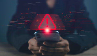 A person looking at a phone with a digital warning sign over it